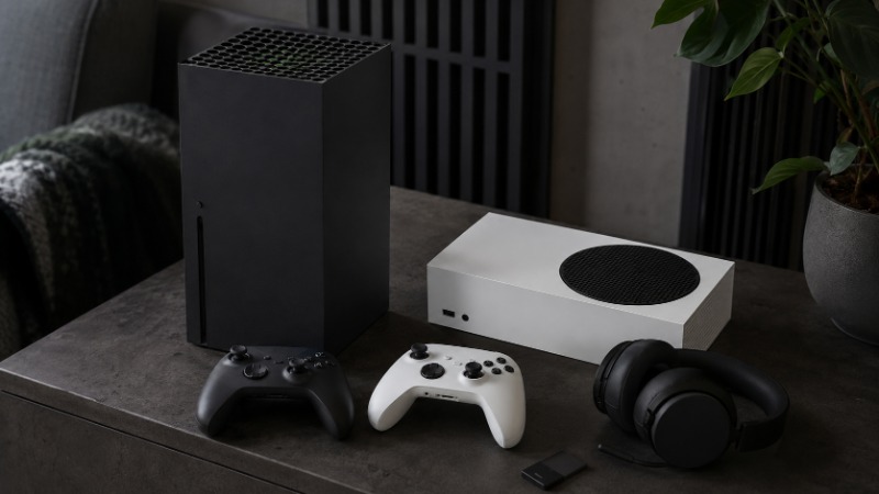 Konzole Xbox Series X a menší Series S vedle sebe s ovladačem na stole